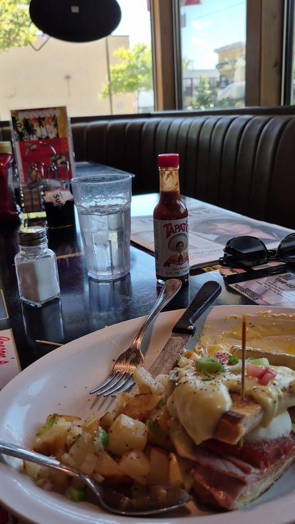 Breakfast sandwiches beside hashbrowns on white plates.